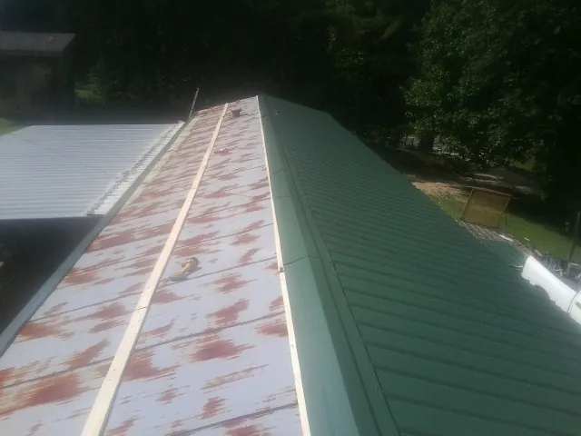 Old rusted panels beside newly installed green metal roofing — Wind Damage Roof Repair by Roofing Brothers in Forestdale
