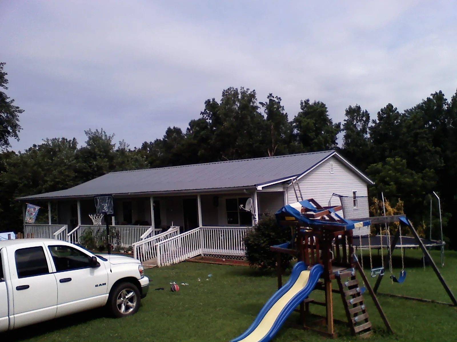 Dark metal roof on a country home with a full length front porch in Forestdale