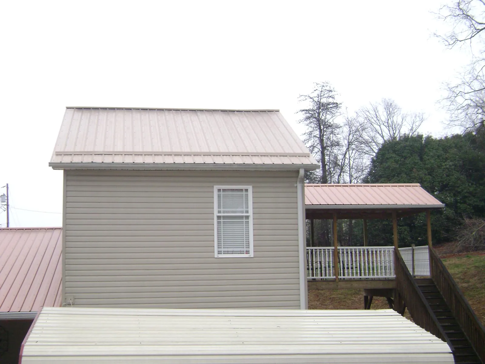 Tan metal roofs on a two story addition and attached porch, from a Roof Replacement job in Forestdale